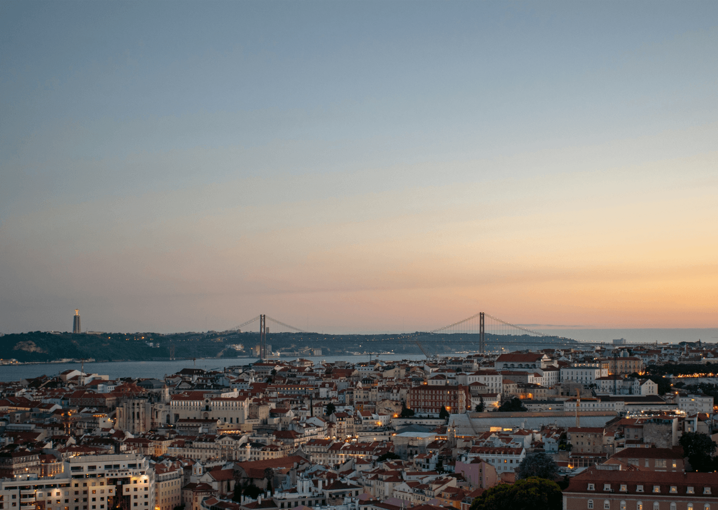 Vista de Lisboa ao pôr do sol com a Ponte 25 de Abril ao fundo.